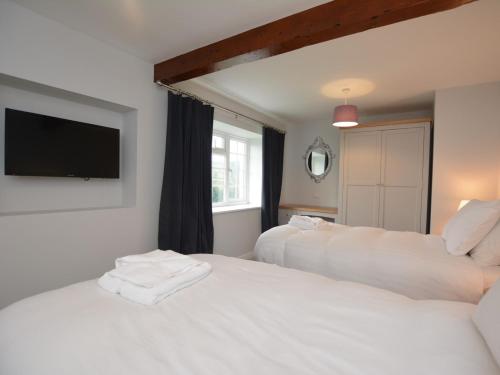 a bedroom with two beds and a tv on the wall at Pengarreg Fawr in Llanilar
