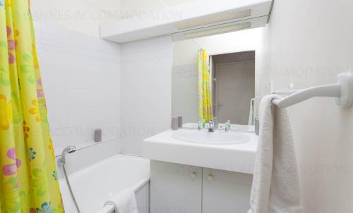 une salle de bain blanche avec un lavabo et un miroir dans l'établissement Lemoine, à Cannes