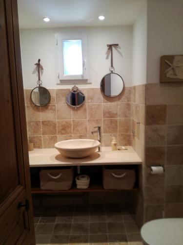 une salle de bain avec un lavabo et deux miroirs au mur dans l'établissement Gite Les Trois Oliviers, à Forcalquier