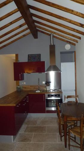 une cuisine avec des placards rouges et une table avec une salle à manger dans l'établissement Gite Les Trois Oliviers, à Forcalquier