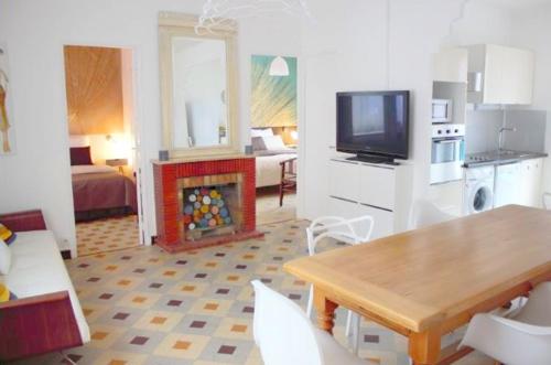 a living room with a table and a kitchen with a television at 2 Chemin Neuf balcon in Gréoux-les-Bains