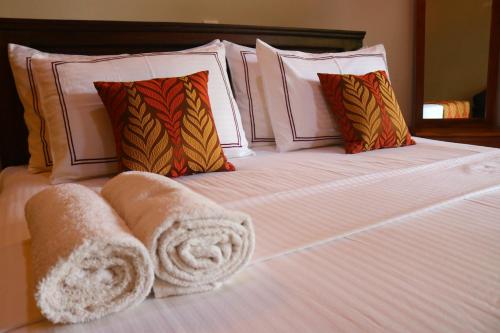 a bed with white blankets and pillows on it at Serenity Sigiri Resort in Sigiriya