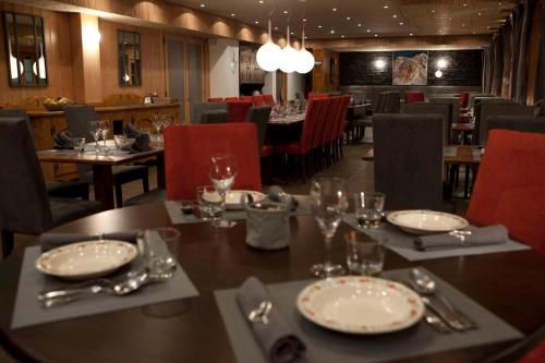 une salle à manger avec une table, des assiettes et des verres dans l'établissement Bellevue, aux Gets