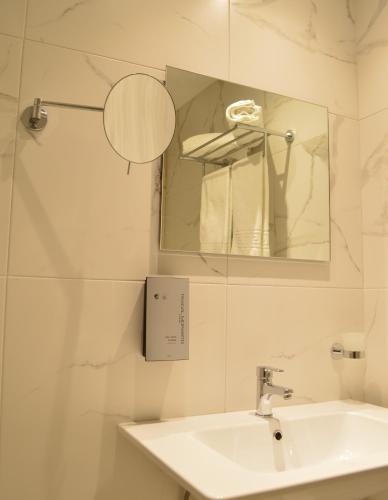 a white bathroom with a sink and a mirror at Alexakis Hotel & Spa in Loutra Ipatis
