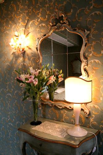 a table with a lamp and a mirror and flowers at Locanda Ca' del Brocchi in Venice