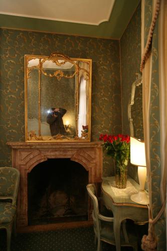 a room with a fireplace with a mirror and a table at Locanda Ca' del Brocchi in Venice