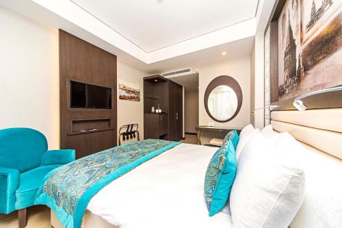 a bedroom with a large bed and a blue chair at Mukarnas Taksim Hotel in Istanbul