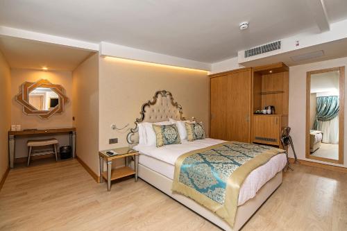 a bedroom with a bed and a desk and a mirror at Mukarnas Taksim Hotel in Istanbul