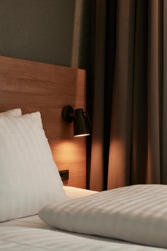 a bed with a white pillow and a lamp on it at Go Hotel Østerport in Copenhagen