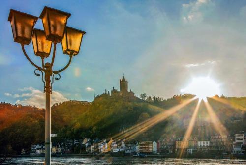 a street light next to a river with a castle at Pension Winnemuller in Cochem