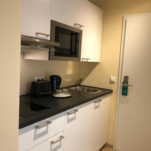 a kitchen with a sink and a microwave at Hotel Select Suites & Aparts in Mönchengladbach