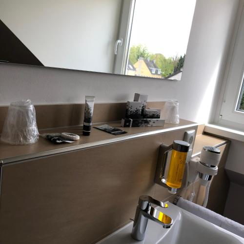 a bathroom with a sink and a mirror above a sink at Hotel Select Suites & Aparts in Mönchengladbach