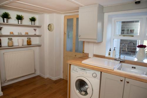 a kitchen with a washing machine and a sink at Charming Corbridge Cottage with Garden in Corbridge