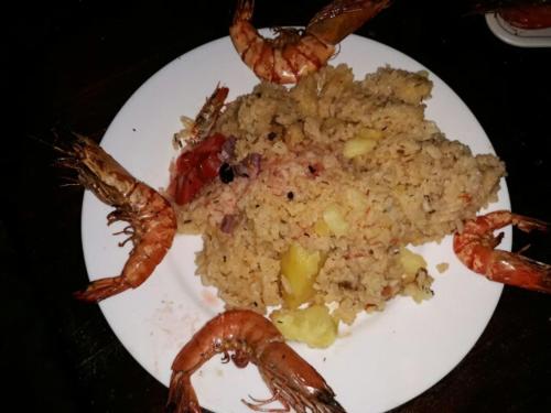 a plate of shrimp and rice on a table at Mango Lodge MSAMBWENI in Kisimachande
