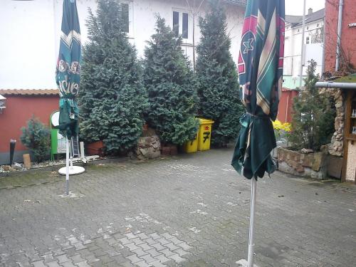 twee gesloten parasols op een binnenplaats met bomen bij Hotel zur Küferschenke in Nierstein