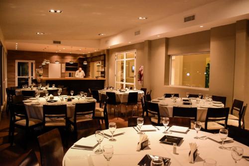 a restaurant with white tables and chairs and a chef at Hostería Atahualpa Yupanqui in Tafí Viejo