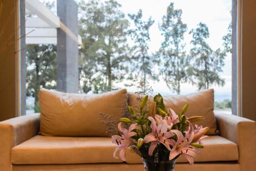 a couch with a vase of flowers on a table at Hostería Atahualpa Yupanqui in Tafí Viejo