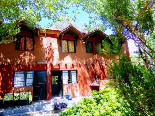 une grande maison en briques avec des arbres devant elle dans l'établissement Cabañas El Challao, à Mendoza