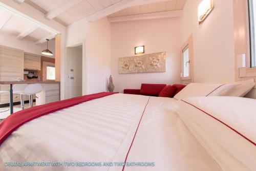 a large white bed in a room with a red couch at Antica Fonte Holiday Homes in San Pantaleo
