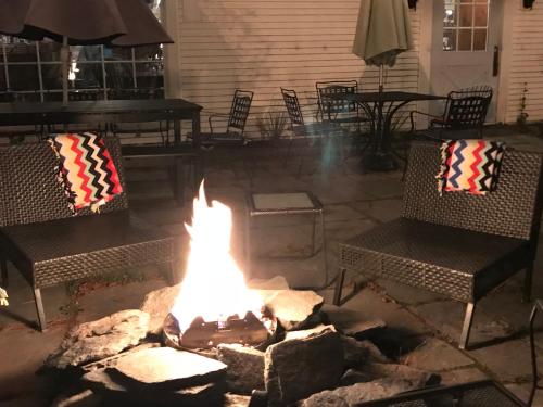 eine Feuerstelle auf einer Terrasse mit Stühlen und Tischen in der Unterkunft The 1896 House Country Inn - Brookside & Pondside in Williamstown