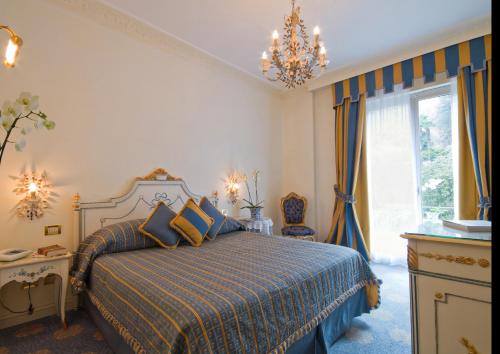 a bedroom with a bed and a chandelier at Hotel Villa e Palazzo Aminta in Stresa