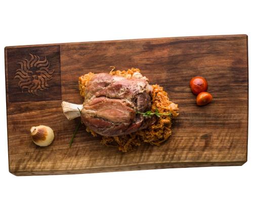 a piece of meat on a cutting board with tomatoes at Hotel Leon & Spa in Arad