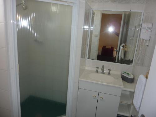 a bathroom with a sink and a shower with a mirror at Atlas Motel in Dubbo