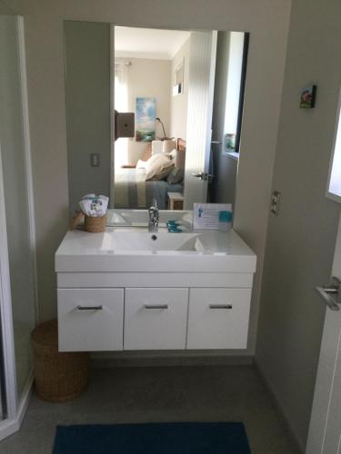 ein Badezimmer mit einem weißen Waschbecken und einem Spiegel in der Unterkunft Abel Tasman Sands BnB in Marahau