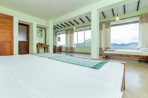 a large bedroom with a large white bed and windows at Jack Tree Lodge in Kandy