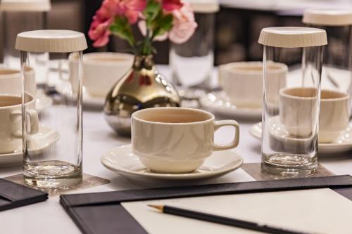 a table with a cup of coffee and a vase of flowers at Pacific Business Hotel in Taipei