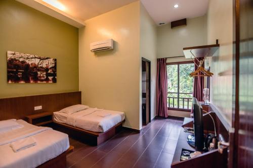 um quarto de hotel com duas camas e uma televisão em Sentosa Villa em Taiping