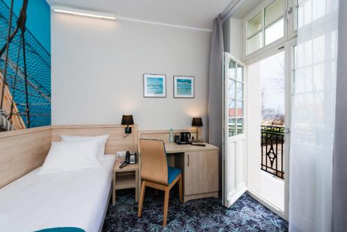 Pokój hotelowy z łóżkiem, biurkiem i oknem w obiekcie Hotel Eureka w mieście Sopot