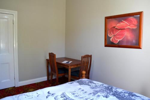 a bedroom with a desk and a table with two chairs at Ithaca 1896 Manor in Busselton