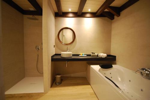 een badkamer met een wastafel, een bad en een spiegel bij Hotel Bujaruelo in Torla