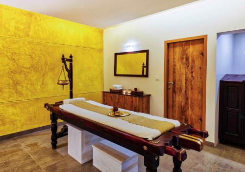 a bedroom with a bed and a yellow wall at Sterling Wayanad in Sultan Bathery