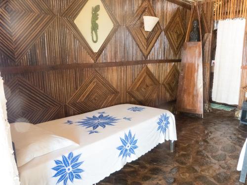 una cama en una habitación con una pared de madera en Le Zahir de l'ile - Iranja, en Nosy Be