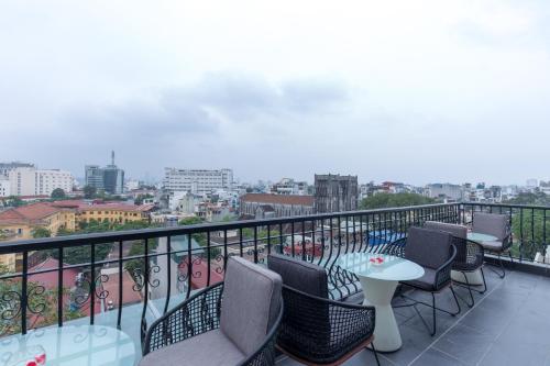 a balcony with chairs and tables and a view of a city at The Chi Boutique Hotel in Hanoi