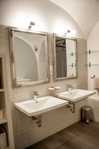 two sinks in a bathroom with two mirrors at 4 Rooms in Maribor