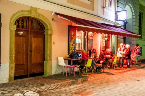 a group of people sitting at tables outside a restaurant at 4Rooms in Maribor