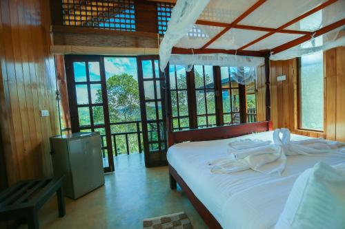 Tina Nature villa في إيلا: غرفة نوم بسرير وملاءات بيضاء ونوافذ