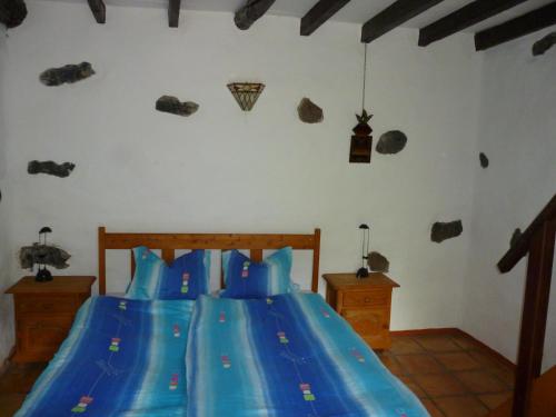 a bedroom with a bed with blue sheets and rocks on the wall at casarno pequena el guro in Calera