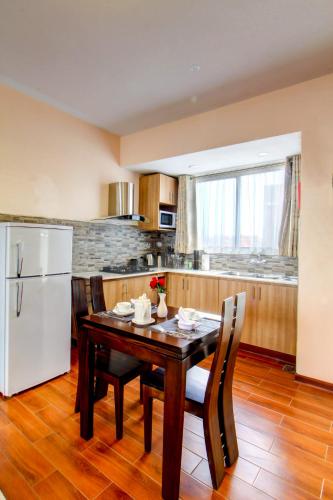 a kitchen with a wooden table and a white refrigerator at Highlands Suites Hotel Apartments in Nairobi