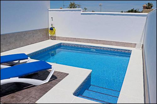 een zwembad met een stoel en een tafel en een blauwe zonneklep bij Casa Rural Zara II in Conil de la Frontera