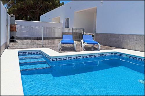 two blue chairs sitting next to a swimming pool at Casa Rural Zara II in Conil de la Frontera