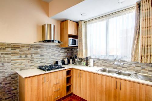 a kitchen with wooden cabinets and a sink and a window at Highlands Suites Hotel Apartments in Nairobi