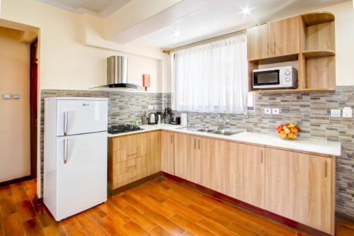 a kitchen with a white refrigerator and wooden cabinets at Highlands Suites Hotel Apartments in Nairobi
