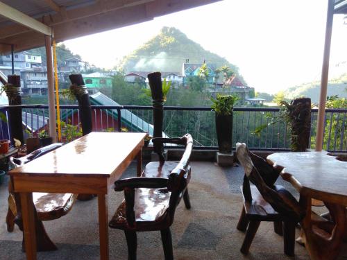 a balcony with tables and chairs and a view of a mountain at Savta Homestay in Banaue