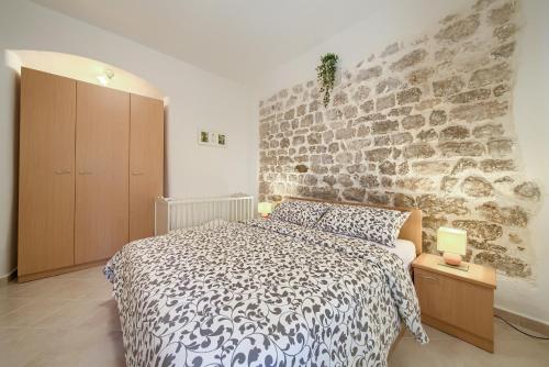 a bedroom with a bed and a stone wall at Hrast in Krk