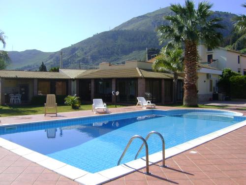 una piscina con due sedie e una casa di Villa Cocus ad Altavilla Milicia