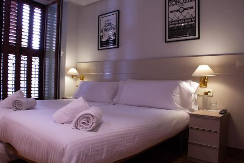 Un dormitorio con una cama blanca con toallas. en Pension Larrea, en San Sebastián